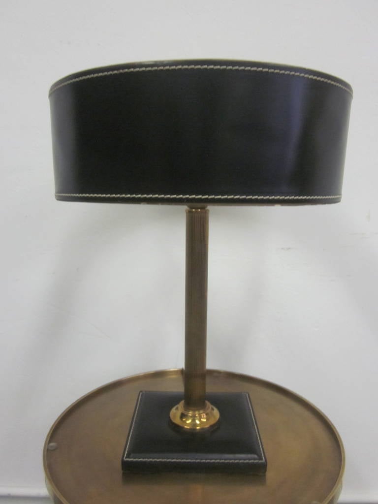 Elegant French Mid-Century Modern hand-stitched black leather table lamp in the modern neoclassical tradition attributed to Hermes with a hand-stitched black leather shade and a fluted solid brass stem. Uitilizes one Edison socket.

Additional