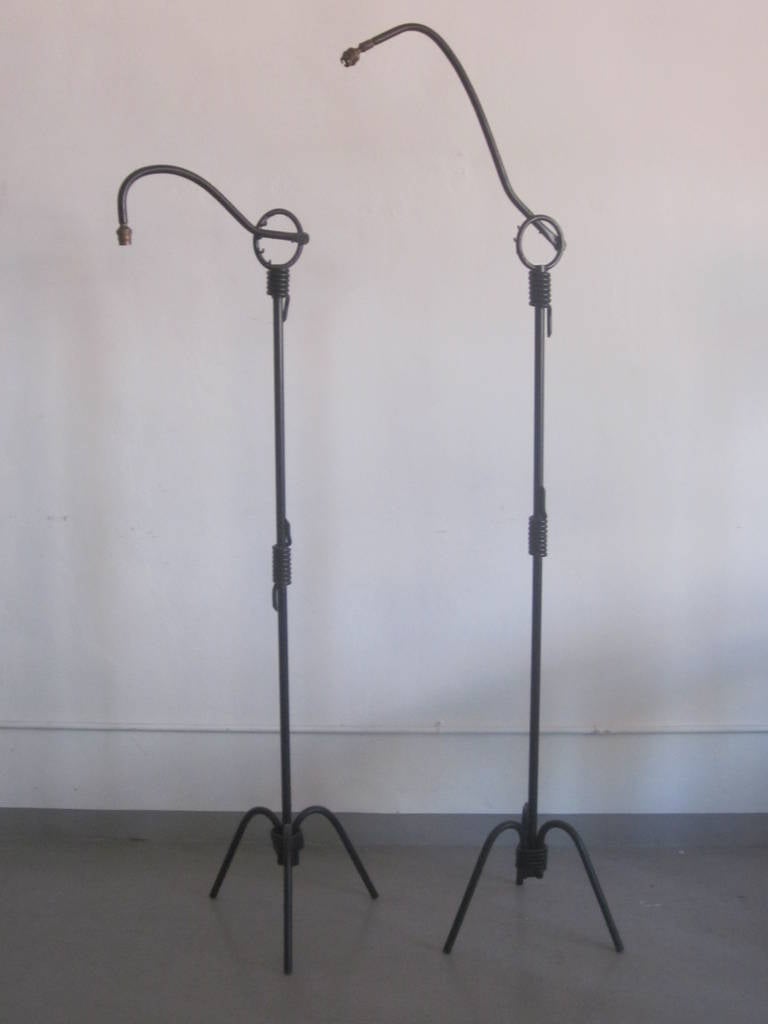 Pair of French Mid-Century Modern standing lamps attributed to Jean Royere in enameled hand-wrought iron that embrace both modern and neoclassical traditions. 

Although the pieces appear as a pair there are slight differences between each. The