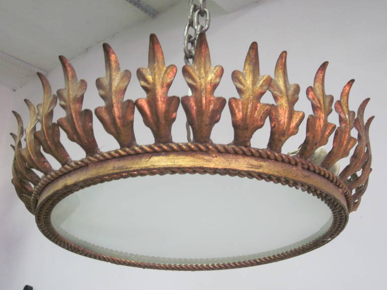 French Mid-Century Modern Neoclassical Flush Mount Fixture / Pendant in gilt iron. The fixture has a frosted glass center which is surrounded by layers of wrought iron rope braiding. Iron acanthus leaves ries from the braiding to simulate the image
