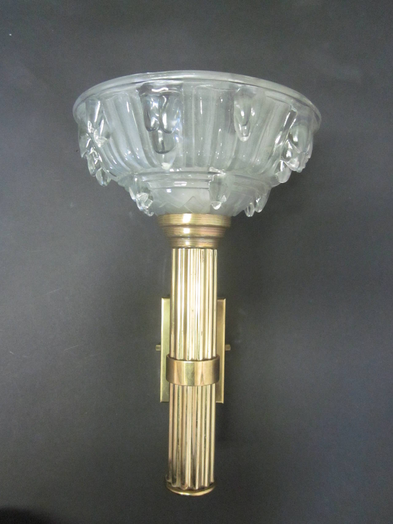 Elegant pair of French Art Deco torch sconces / wall lights with fluted stems in brass and opaline crystal glass diffusers. The glass design and methods are typical of the work of René Lalique. Sold and priced by the pair.