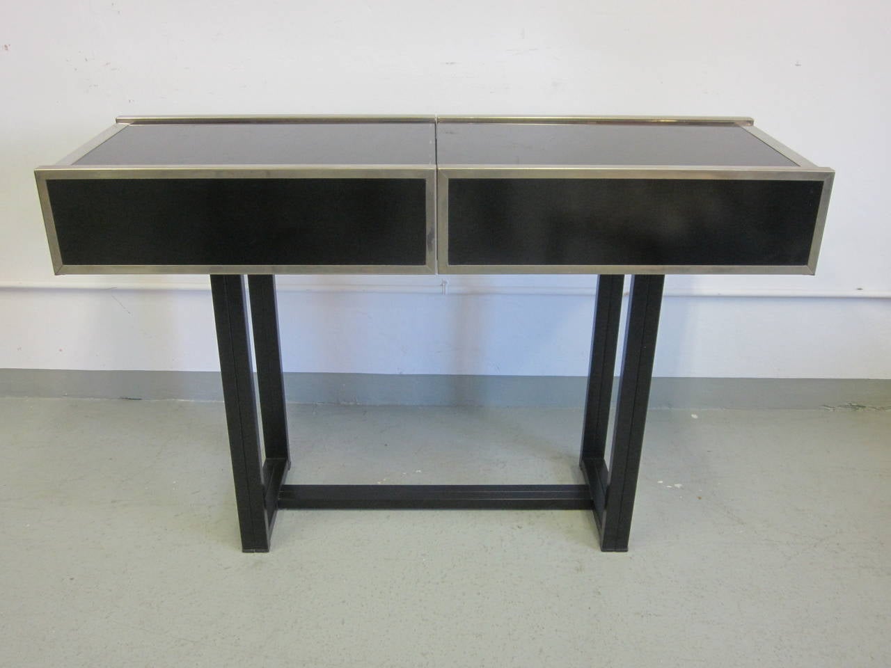 An elegant Italian design / Mid-Century Modern, nickeled and black glass console / sofa table / bar attributed to Willy Rizzo with a nickeled internal storage space compartment (a bar) that enables the piece to expand from 48" when closed to as