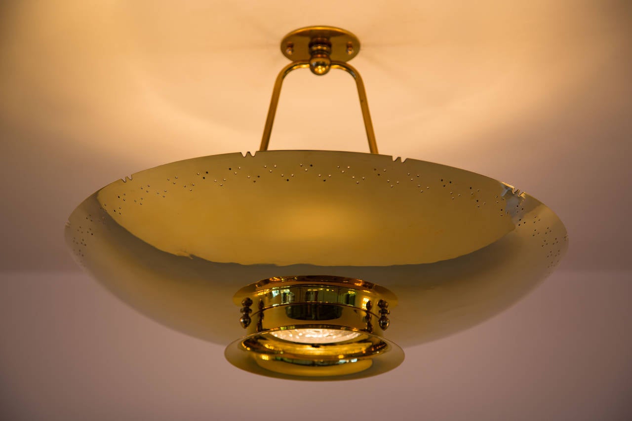 Perforated brass pendant with molded glass downlight.