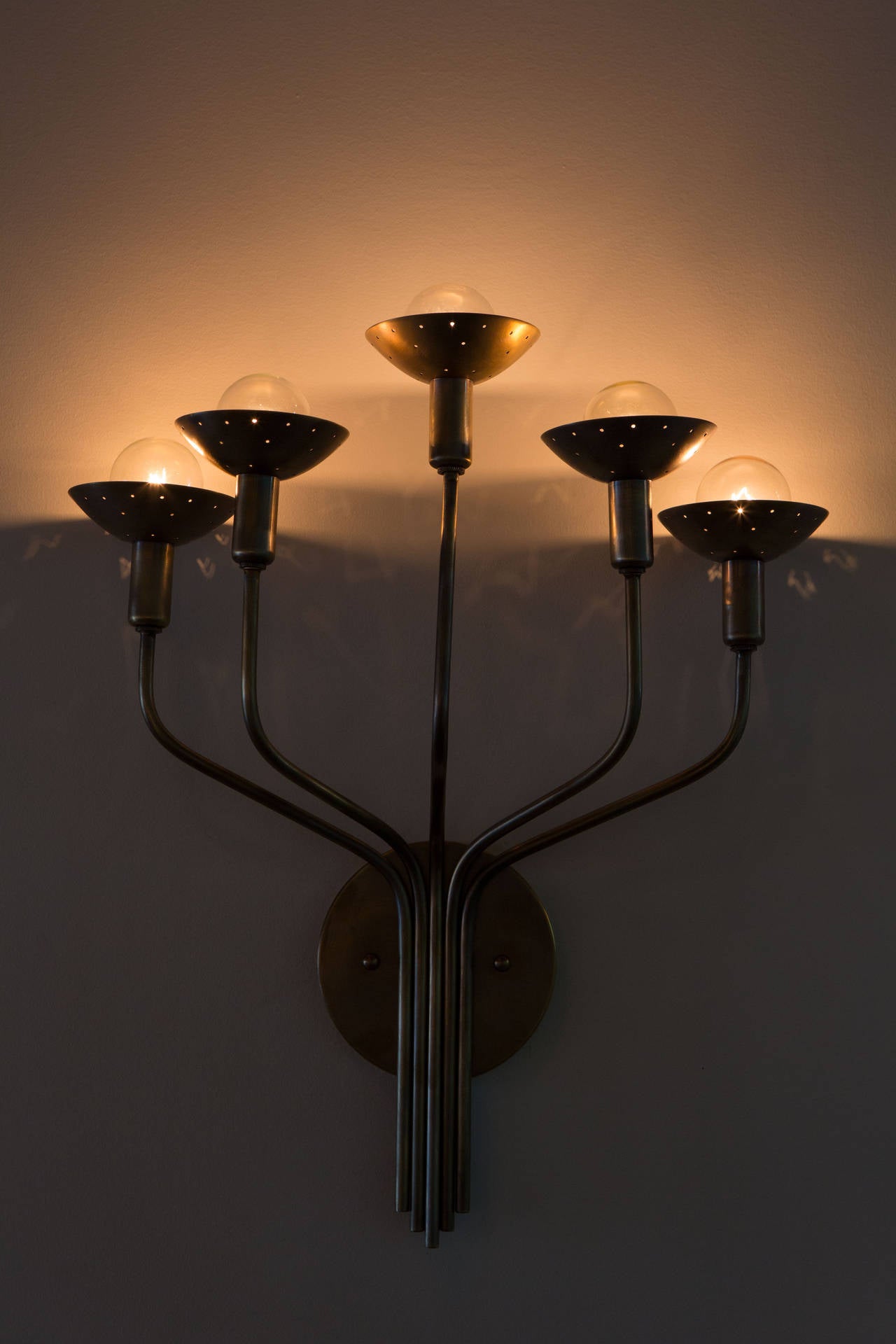 Five-arm brass sconce with perforated shades.