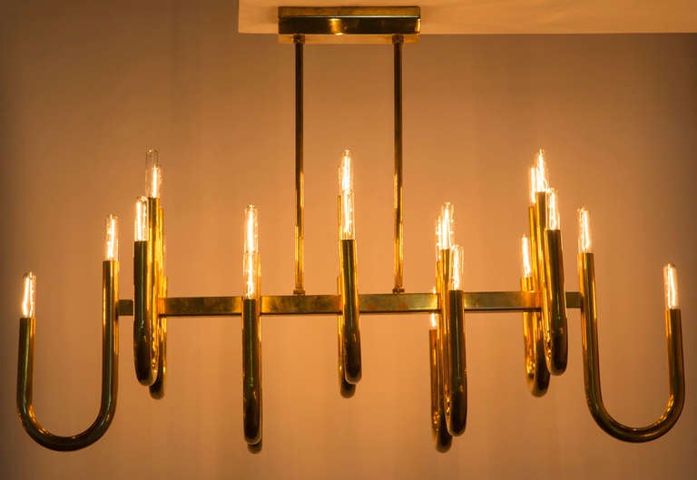 Large scale rectangular chandelier with twelve J shaped brass tubes.