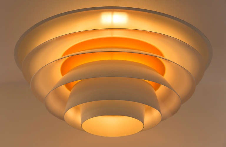 White co-centric shades wrap around a single bulb 
that illuminates the orange center. Flush mount and 
perfect  scale for a large room.