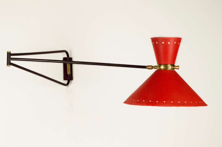 Rene Mathieu for Lunel sconces.
Single double shade large scale wall sconce.  Black enamel arm with brass accents.  Red enamel star perforated shades with lights in both upper and lower shade.  Each light has its own switch.  
Each light uses a