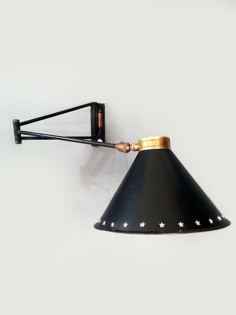 Hard to find, mid century wall sconce.  Articulated arm and pivoting head allow the light to be directed in all directions.  This light has a black enamel aluminum shade with the star motif.  The light has its original switch on the wall support and