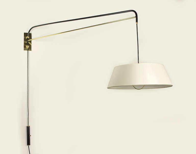 This graceful wall sconce is hand crafted with a black enamel finish and polished brass. An elegant linen shade diffuses a soft light. This fixture is adjustable; the switched counter weight system allow for height adjustments while the arm swivels