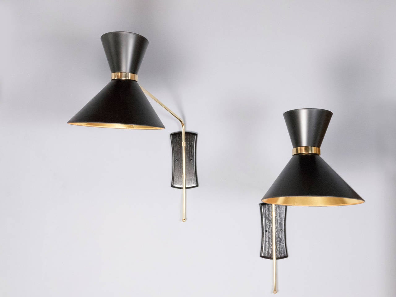These elegant brass swing arm sconces with double black opaque shades with gold foil lining create a very versatile lighting source. The pivoting arm and swiveling head are fitted with two sockets providing both up and down light. The backplate is