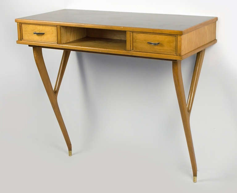 This elegant 1950's Beech console has beautiful tapering legs accented with brass caps of the feet.  Original black formica top in great condition.  The table has two drawers with brass hardware.  Table has two mounting brackets to attach it to the