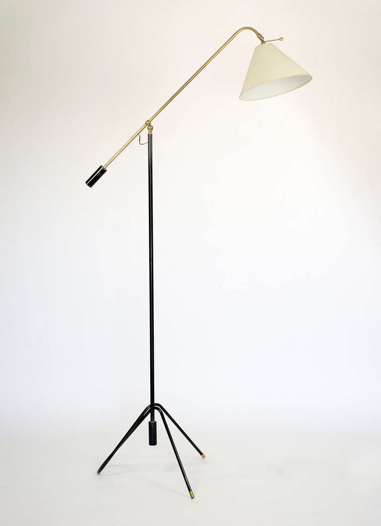 This mid century French floor lamp designed by Rene Mathieu has an unique tripod base, a single steel tube with a stylish twist.  The lamp's construction in brass and black enamel steel provided for a very versatile source of light. The lamp is