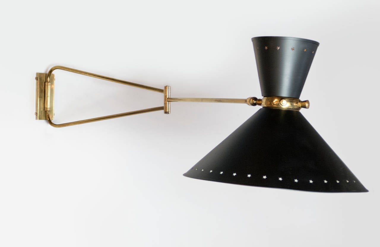 Pair of 1950's Rene Mathieu sconces edited by Lunel. This medium sized pair has the metal double shades with the perforated star motif.  Provides up and down light with the double socket in each diffuser. Brass accents have been re-polished. Shade