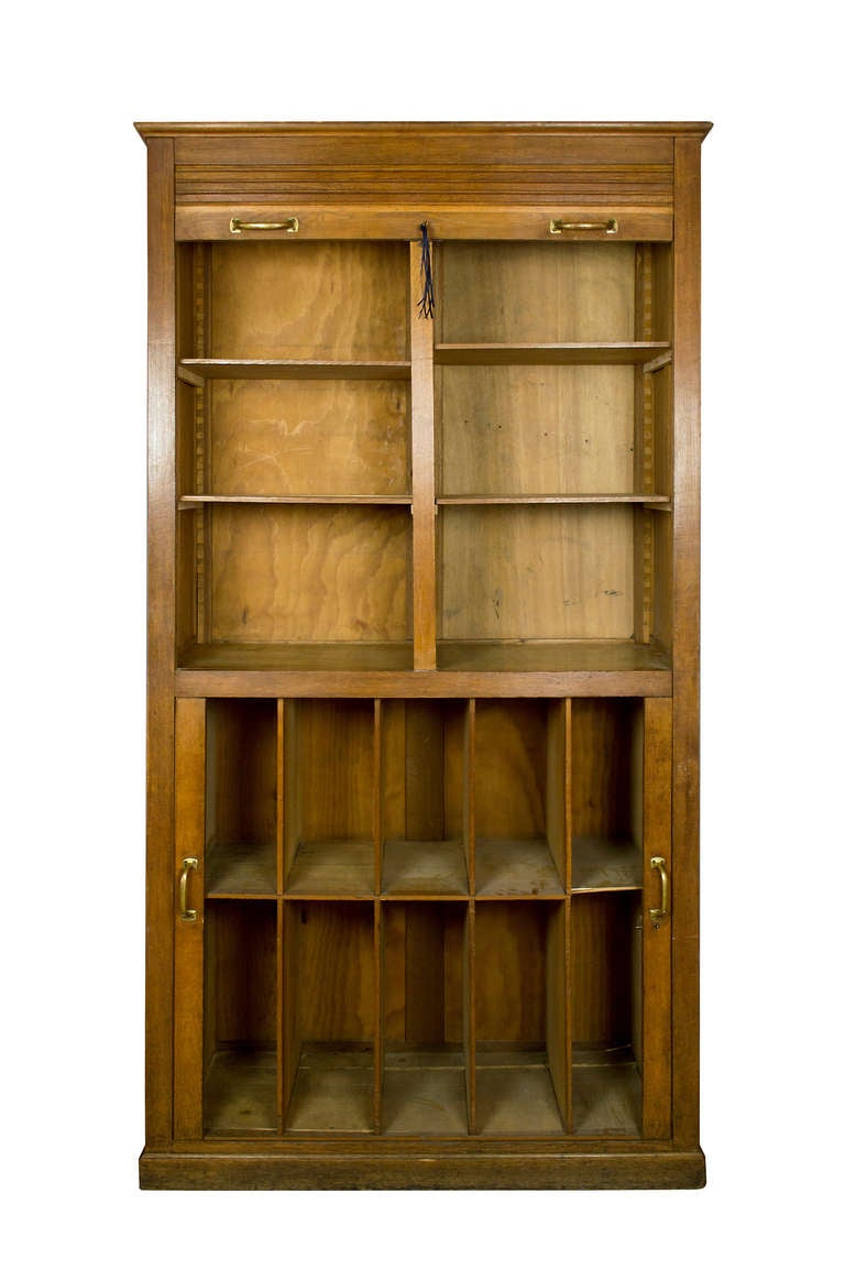 This oak cabinet has two compartments.  The lower section has fixed shelves  and the doors roll back horizontally.  The upper compartment is divided in two parts with shelves which can adjust, the door rolls up vertically.  
The compartments are