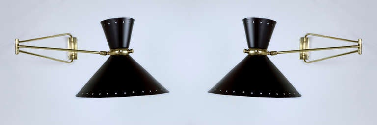 Two 1950s medium-sized wall sconces designed by Rene Mathieu. The frames are in polished brass, this double shade model with the perforated star motif has two independent sockets. The various articulated elbows create a very versatile light. The