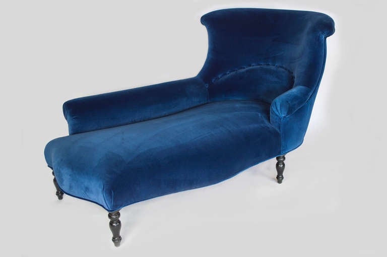 This chaise longue has elegant lines.  It is covered in a Navy blue velvet.  The turned legs has an ebony finish.  Very comfortable.