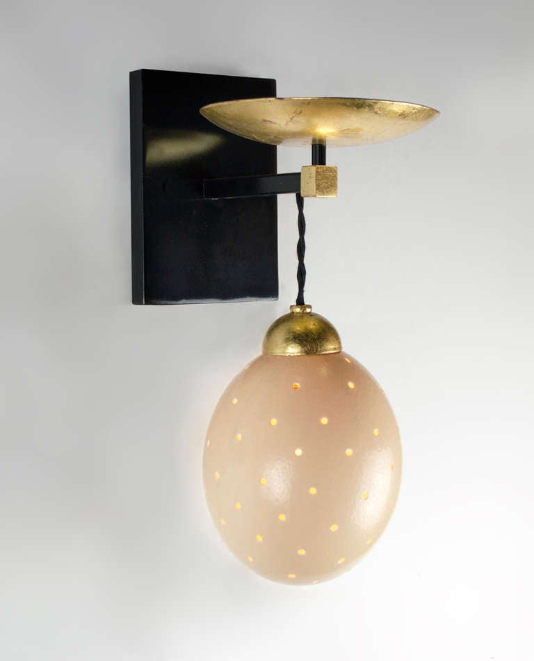 This unique wall sconce has  real ostrich egg diffusers.  The steel frame with an enamel finish and gold leaf accents.  It provides a warm light.  Each light uses one candelabra base bulb.  25 watts max.