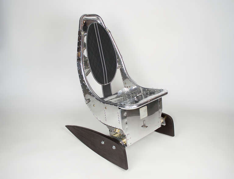 Polished aluminum jet fighter seat from 1965.  This chair was manufactured for a C-130 military jet.  One of four creations from these chairs by Chris Palermo.  The seat has been ingeniously fitted on an ebony wood frame transforming it into a one