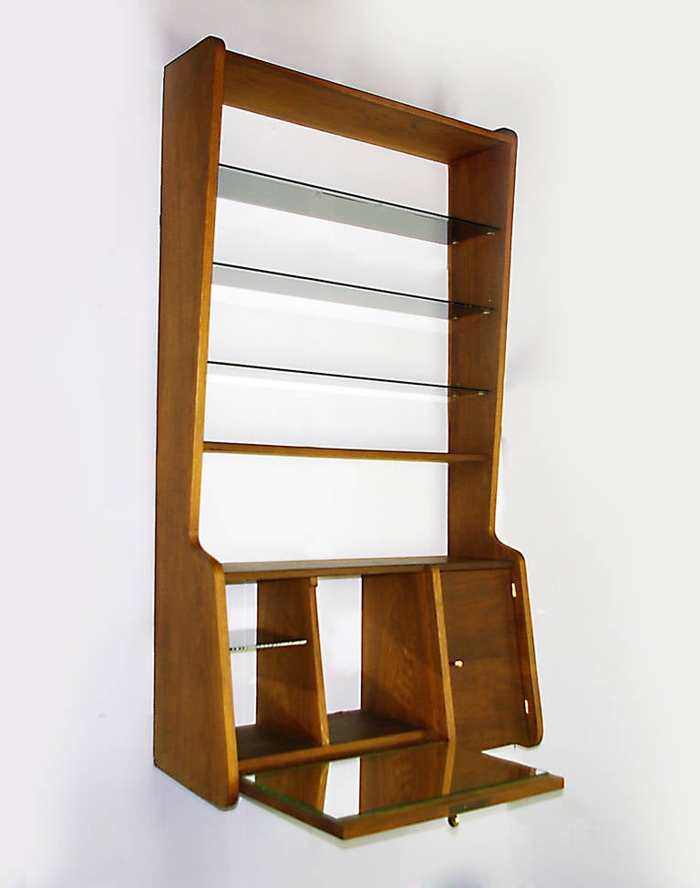 Remarkable oak wall mounted bar.  Flip down serving area with mirrored surface   Lots of storage spaces for glasses or bottles.  Adjustable smoked glass shelves.  Brass accents and keyed serving area.  Other furniture from the same series are