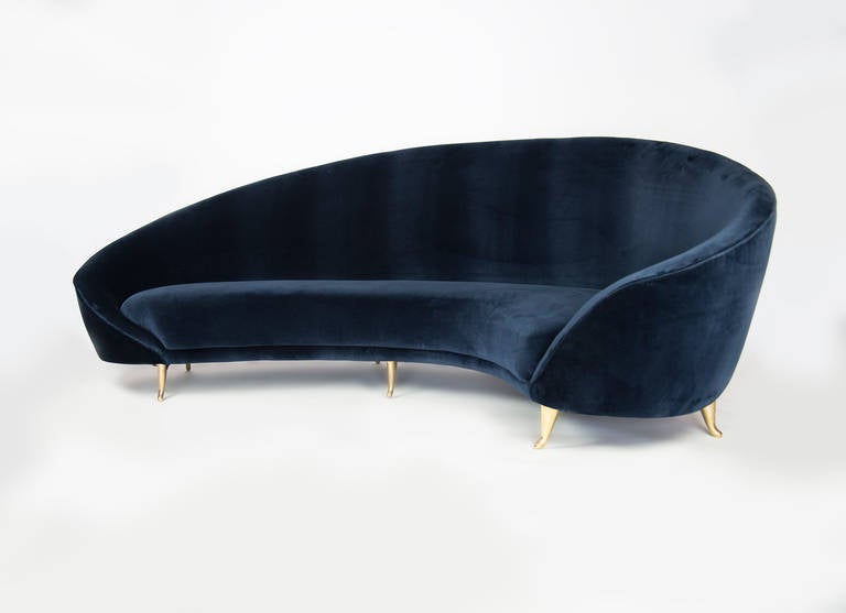 This chic sofa, reminiscent of the 1960s, has elegant lines with gracious curves. The brass feet add to its sophistication with their delicate design. It will surely be the focal point of any room. The kidney shape of the sofa provides plenty of