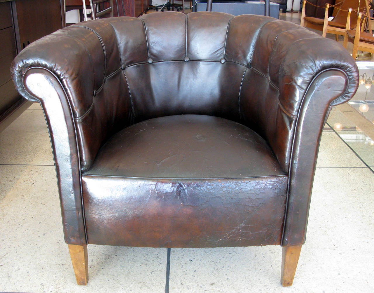 Single leather club chair from Denmark upholstered in dark chocolate, patinated leather. Leather is very old and a bit fragile with cracking on the arms, seat and sides. Wooden legs. Seat height: 18