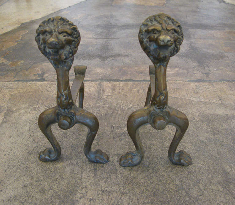 Pair of aged brass lion head andirons.  Beautiful patina.  These andirons are quite shallow/petite & would be perfect in a small fireplace.