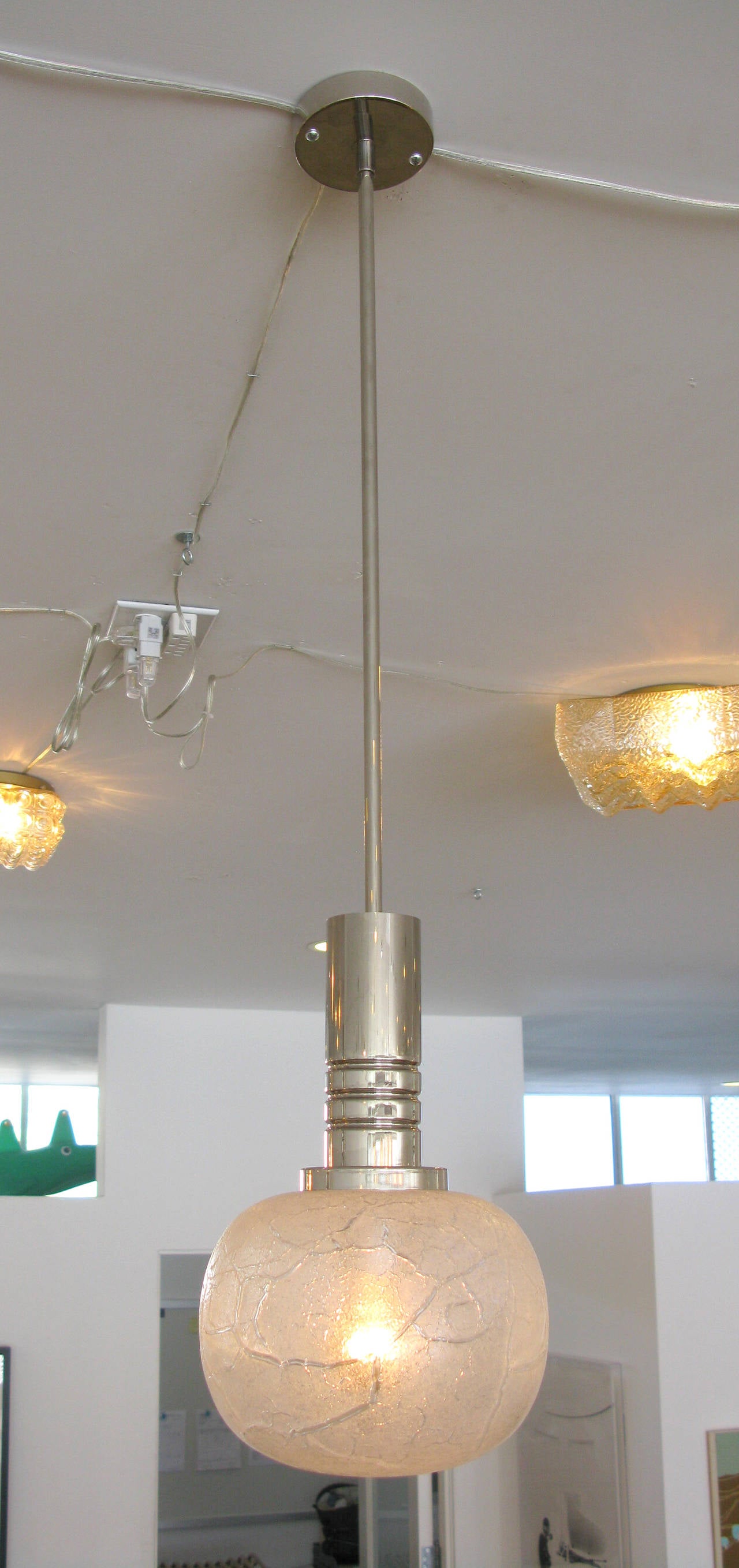 Set of 3 pendant lights with a crackled ice pattern hung from polished nickel ceiling mounts.  Glass globes alone measure approximately 6