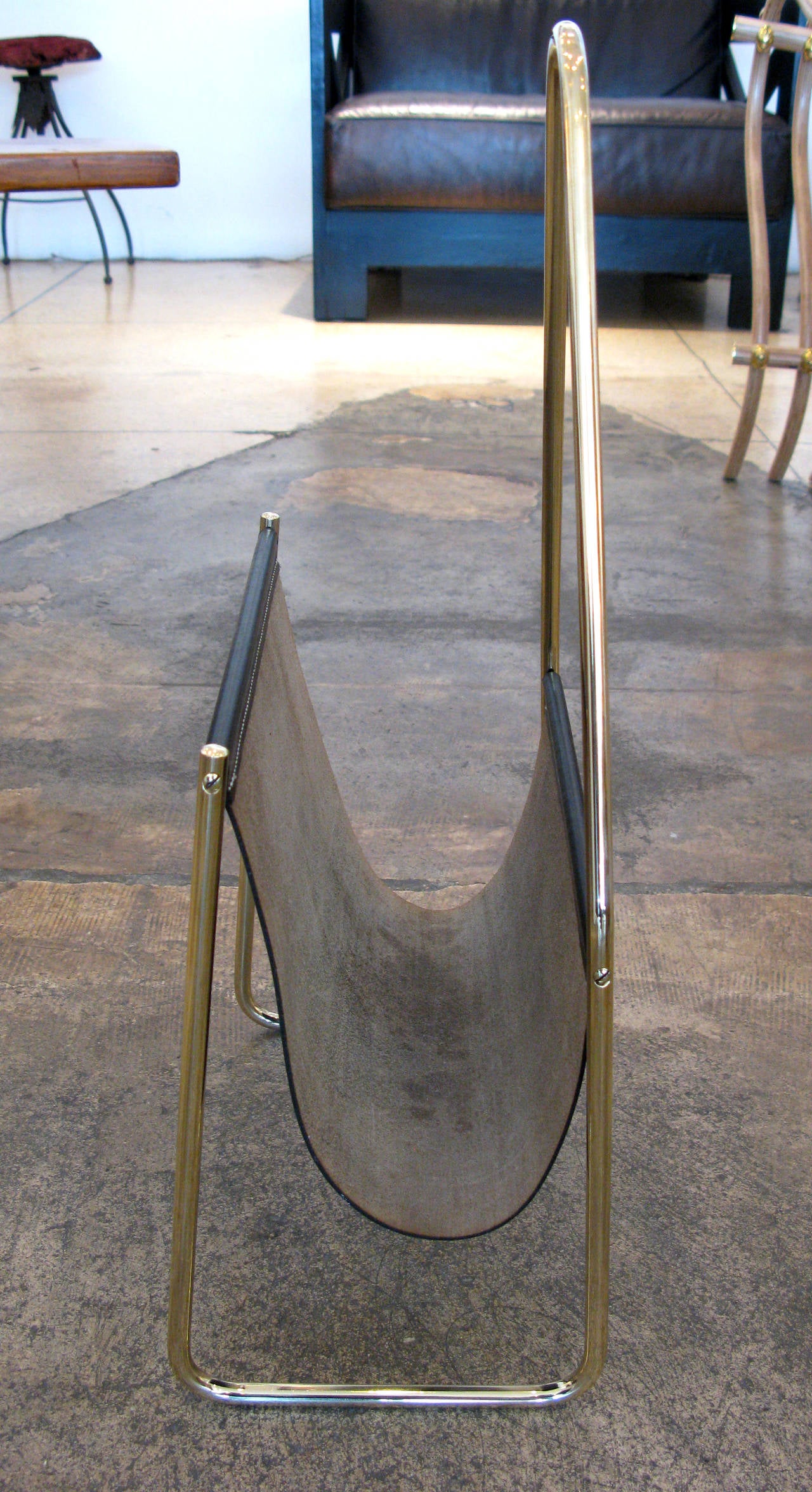 Brass and leather magazine rack by Carl Auböck. Produced in the 1950s in Vienna. Aged black leather and polished, hand-sculpted brass.

