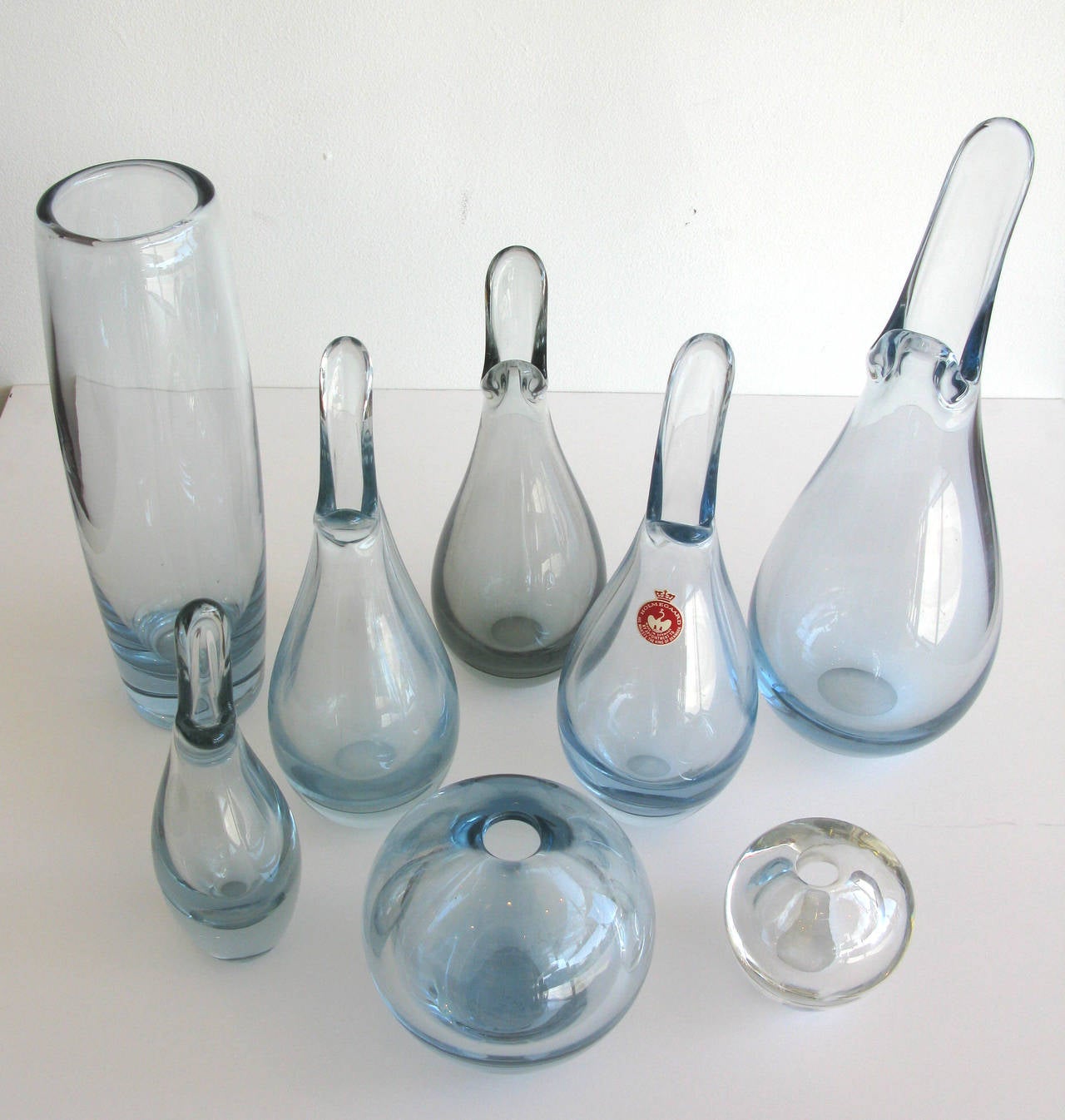 Gorgeous eight piece set of Holmegaard glass from Denmark. Designed by Per Lutken. Colors range from clear to a light smoky blue. One bottle retains the original Holmegaard label. Dimensions listed are for the largest piece in the set.

* ON SALE