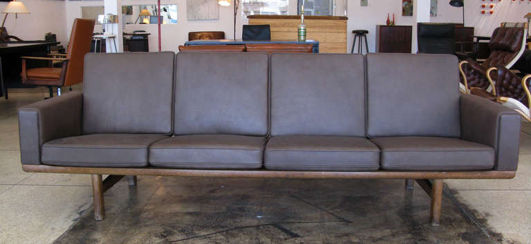 Four person sofa designed by Hans J. Wegner and produced by GETAMA, Denmark. Cushions are upholstered in soft, chocolate brown leather. Oak frame is stamped 
