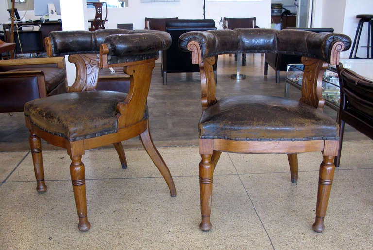 Pair of beautifully aged leather & oak armchairs.  Curved backs with carved oak frames.  Leather has great patina due to age.  Seat height measures 19.75