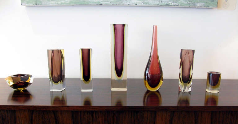 Beautiful 7 piece Murano Sommerso art glass set designed by Flavio Poli for Seguso.  Layers of clear, burgundy, gold & pale blue glass.  Includes 2 faceted vases, 2 square vases, 1 teardrop vase, 1 faceted bowl & 1 small glass.