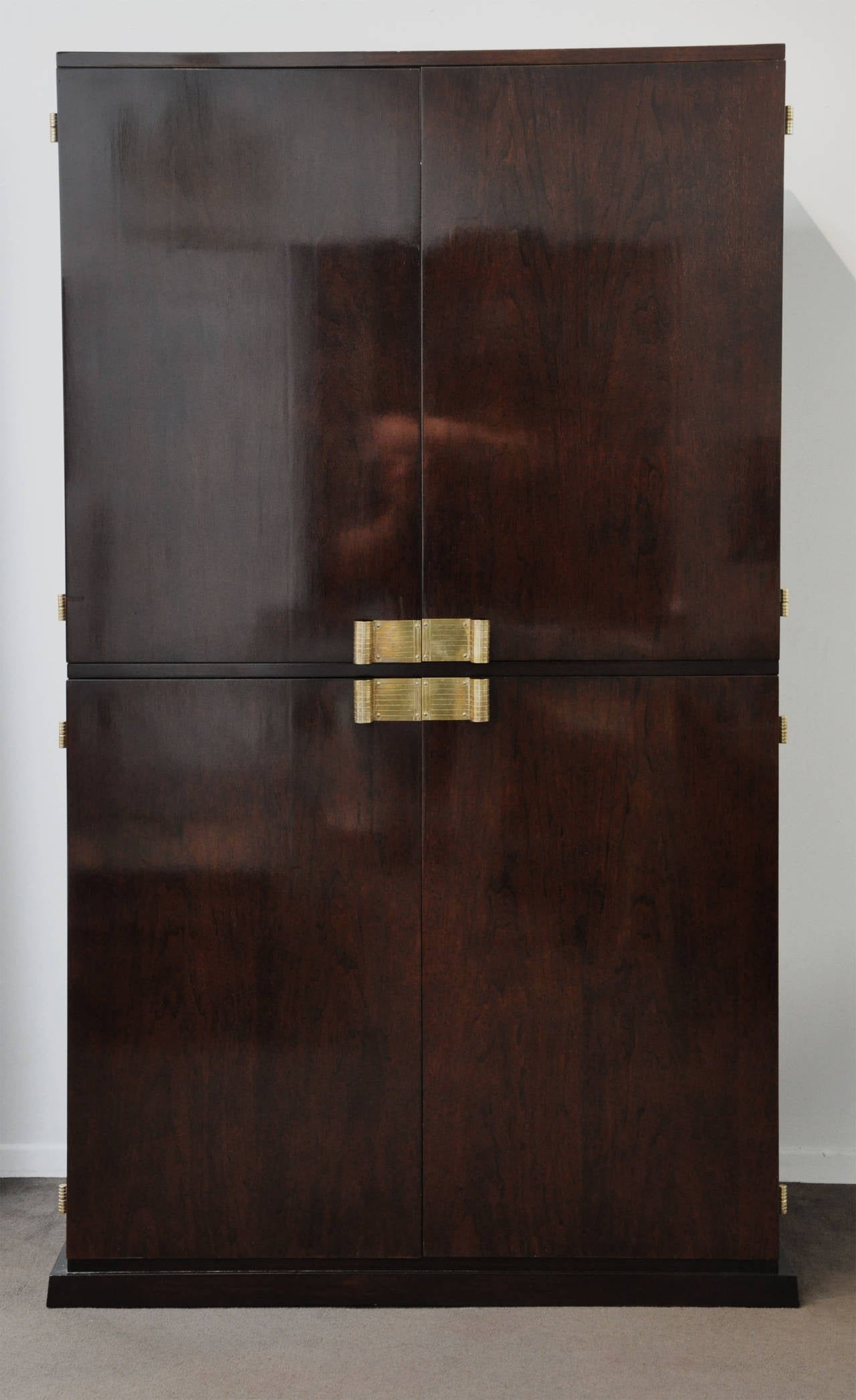 Handsome, illuminated bar cabinet designed by Tommi Parzinger (American, 1903-1981). Beautiful finished walnut cabinet with the following features: Illuminated bar, original blue lacquered interior, brass pulls and hinges, mirror, glass shelves, two