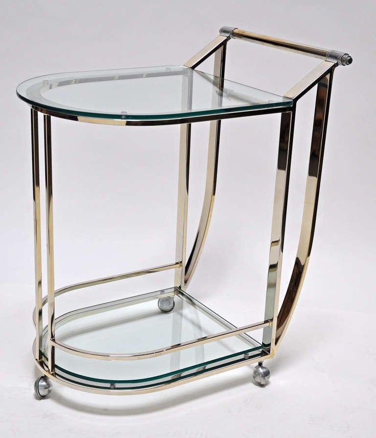 Serving cart featuring polished brass with glass shelves. Quality design and craftsmanship.