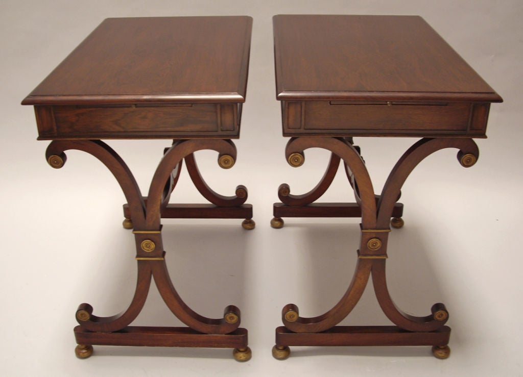 Pair of finished mahogany side tables/nightstands by Grosfeld House. Original gilded details. Each table features two leather top extension that slides out from either side. Price is for the pair.