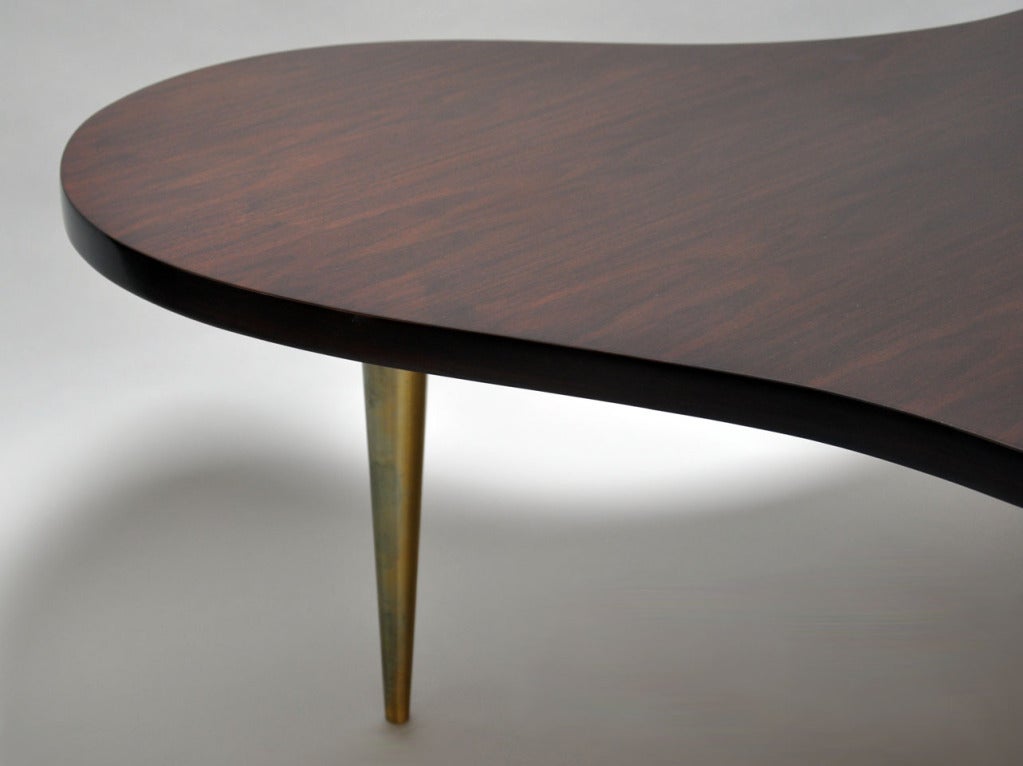 Flowing free form walnut coffee table with brass legs. Designed by T.H. Robsjohn Gibbings for Widdicomb. Retains original label