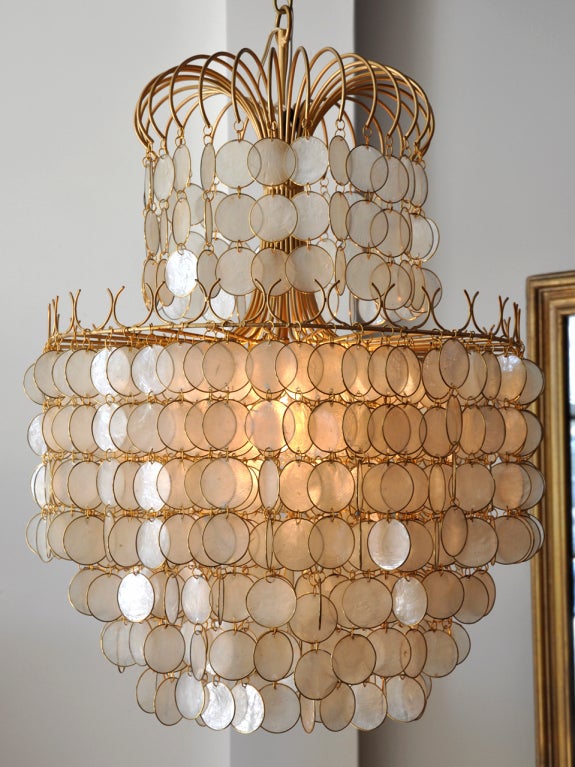 Capiz shell hanging chandelier. Each round section of shell is trimmed in brass. The pieces are linked together and  hang freely from a gold metal frame.
