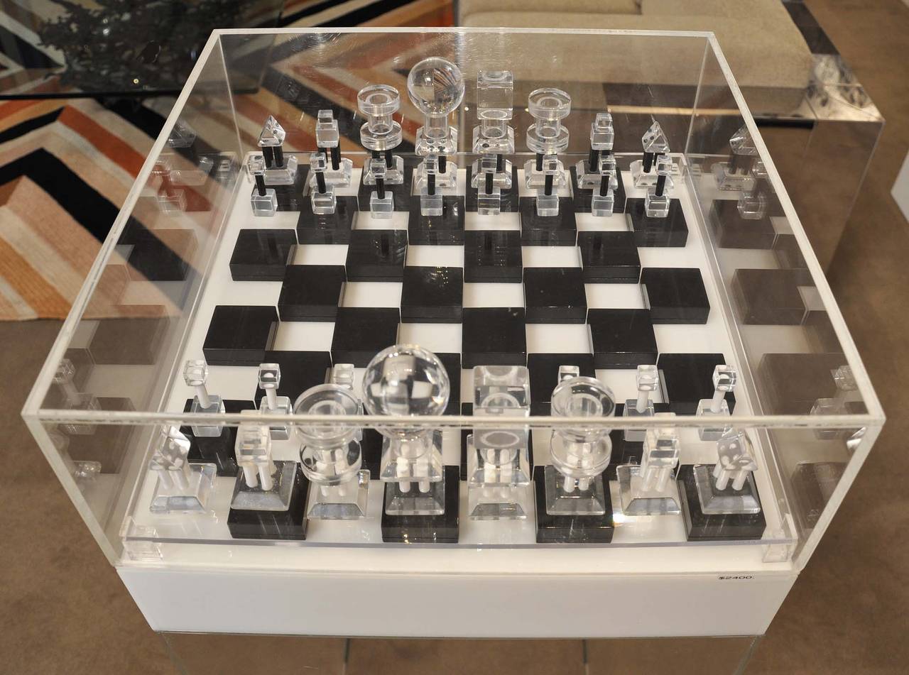 1970s, acrylic black and clear chess set. The board is black, white and clear acrylic. The black sections of the board pop open for checker storage. (there are no checkers included) A clear acrylic cover keeps the set in place while not in use.