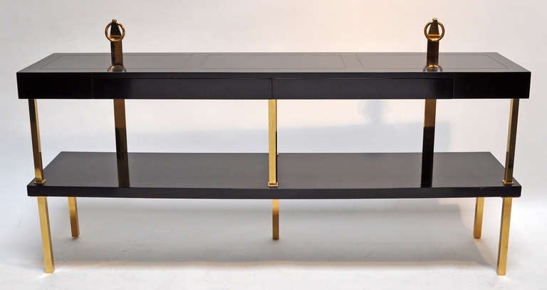 This 66 inch console table features two drawers. Polished brass legs and fittings make this an elegant design. Top quality design and construction.