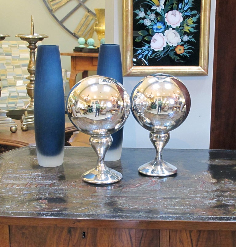 A rare pair of American mercury glass gazing balls also known as the 'silent butler'; each in two joined parts with blown ball resting on a tapering stem and round base; pontil mark to underside