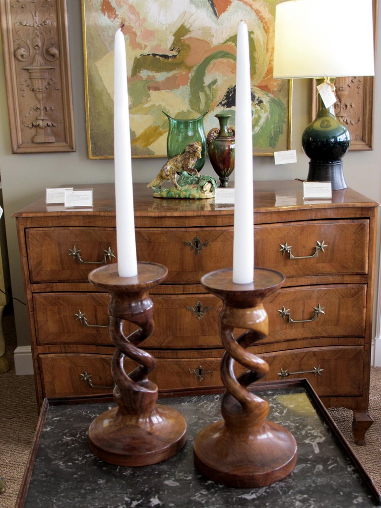 A richly-patinated and well-carved pair of English treenware barley twist candlesticks; each of robust scale with well-carved spiraling openwork support over a splayed base