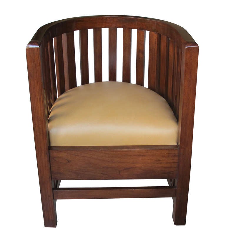 A handsome pair of English arts and crafts black walnut barrel-back chairs; each of pegged construction with incurved openwork slatted back over a u-shaped leather seat; above a plain apron all raised on short square supports