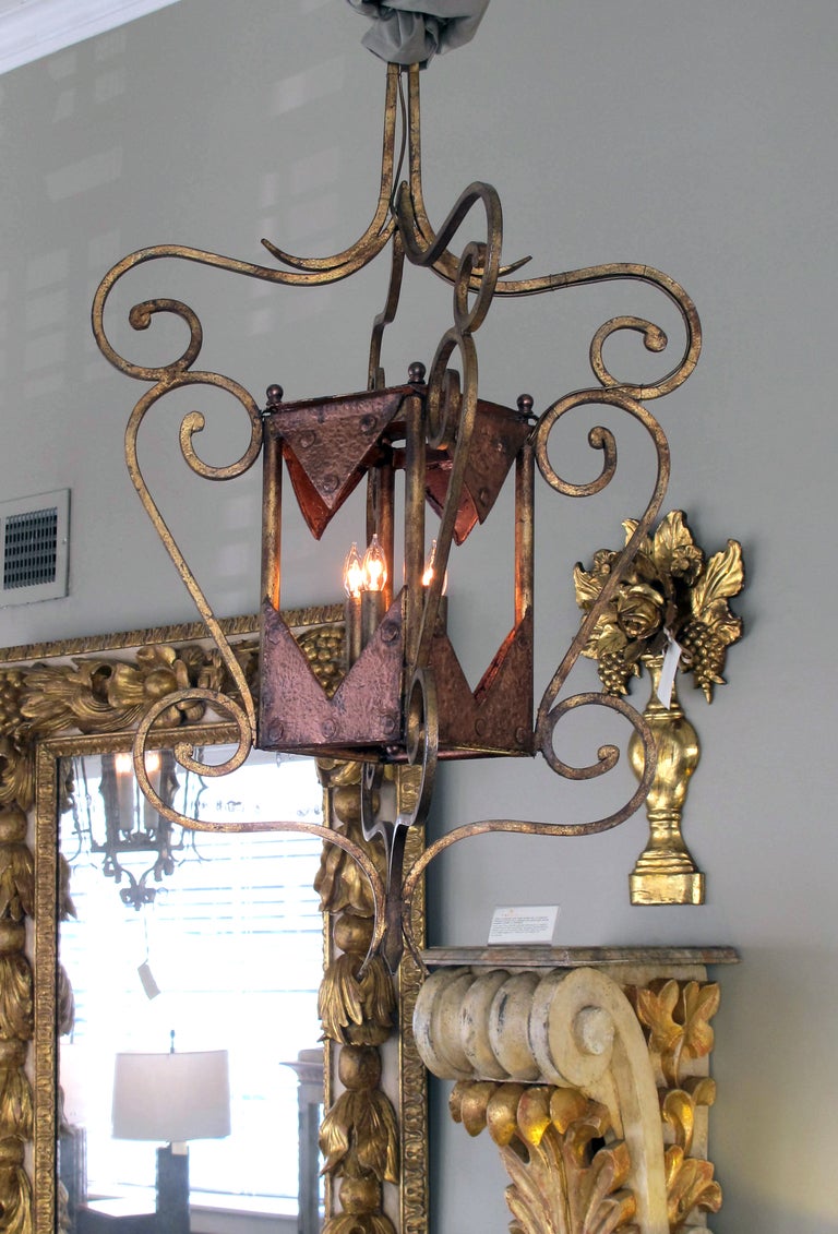 A unique French transitional arts and crafts 4-light gilt-iron quadrangular lantern; the hand-wrought 4-light lantern with rectangular light box surrounded by curvaceous scrolling iron work