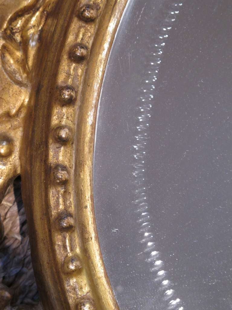 A charming Napoleon III oval-form reticulated carved giltwood mirror with grapevine motif; the original oval plate with etched border within a well-carved openwork frame depicting a meandering grape vine