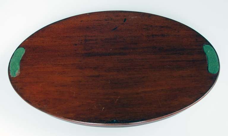 A large-scaled and finely inlaid Victorian mahogany oval butler's tray; the oval tray with raised gallery centering a floral medallion flanked by bell flowers, ribbons and swags; fitted with brass handles