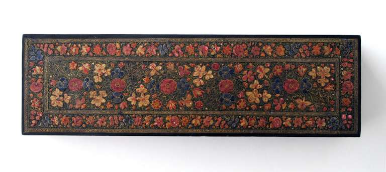 An intricately decorated Kashmiri rectangular lacquered box; the covered box adorned overall with finely painted flower heads and foliate vines.