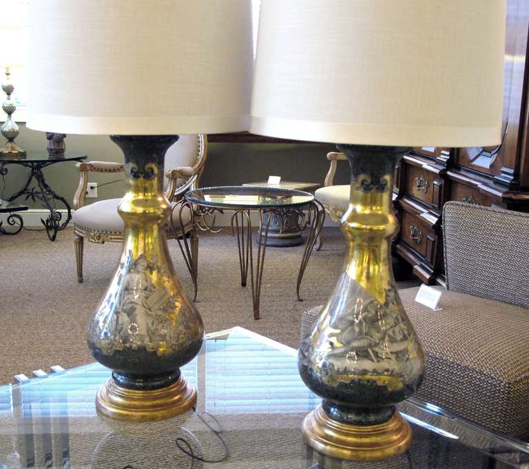 A chic and good quality pair of Italian 1960's Fornasetti style verre eglomise lamps; each bulbous lamp with glass encased gilded surface adorned with rococo figures
