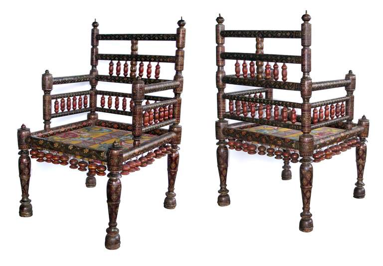 A rare pair of Kashmiri lacquered armchairs; each with upright openwork back and arms with turned stiles raised on baluster supports; the apron with hanging vasi-form pendants; lacquered overall with fine floral and geometric designs