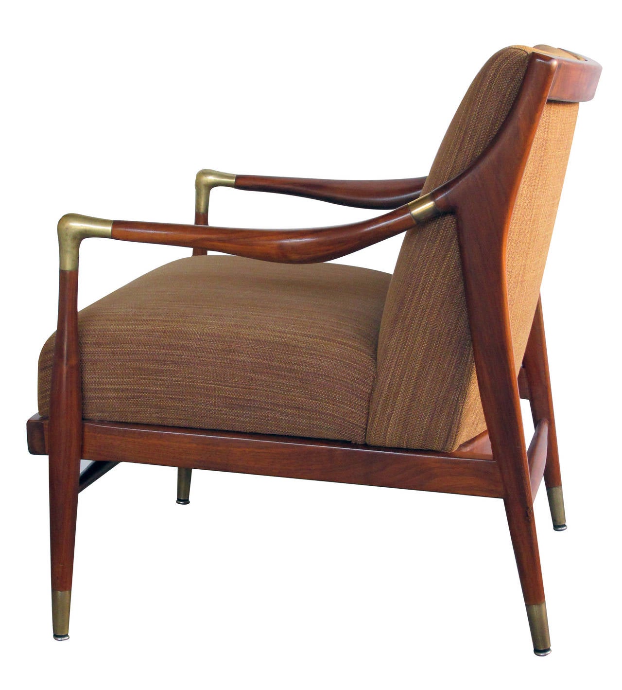 A sculpted pair of Danish modern 1960s brass accented lounge chairs; attributed to Ib Kofod-Larsen; each with incurved back above an upholstered seat flanked by shaped arms with brass fittings; raised on tapering supports with brass feet.