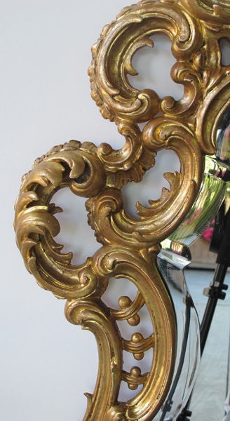 A finely carved French Napoleon III cartouche-shaped mirror; the original beveled plate of cartouche form within a conforming reticulated frame of lively rocaille carving of foliate, shells and c-scrolls