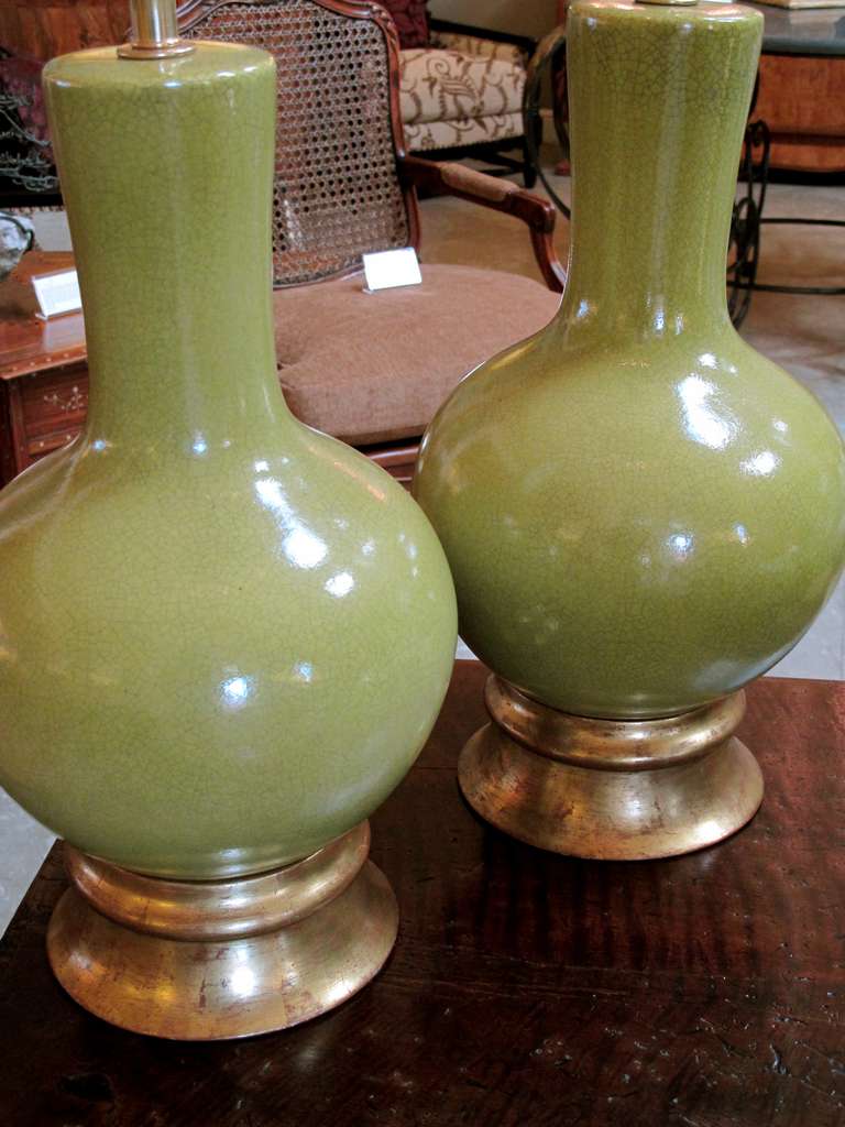 A stylish pair of American mid-century apple-green glazed pottery lamps designed by Paul Laszlo made by Wilshire House, Beverly Hills; each with long flaring neck above a portly body resting on a giltwood base; all in a crackled acid green glaze